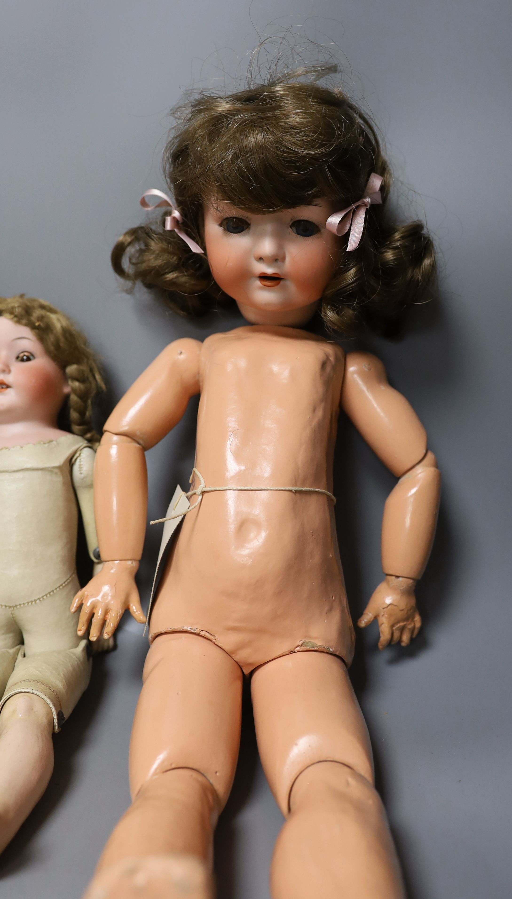 A kid leather bodied jointed limb open mouth Heubach bisque headed doll together with two other bisque headed dolls and a boy doll (damaged)